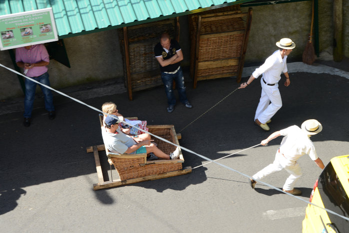 Touris werden in Schlitten den Berg runtergerutscht